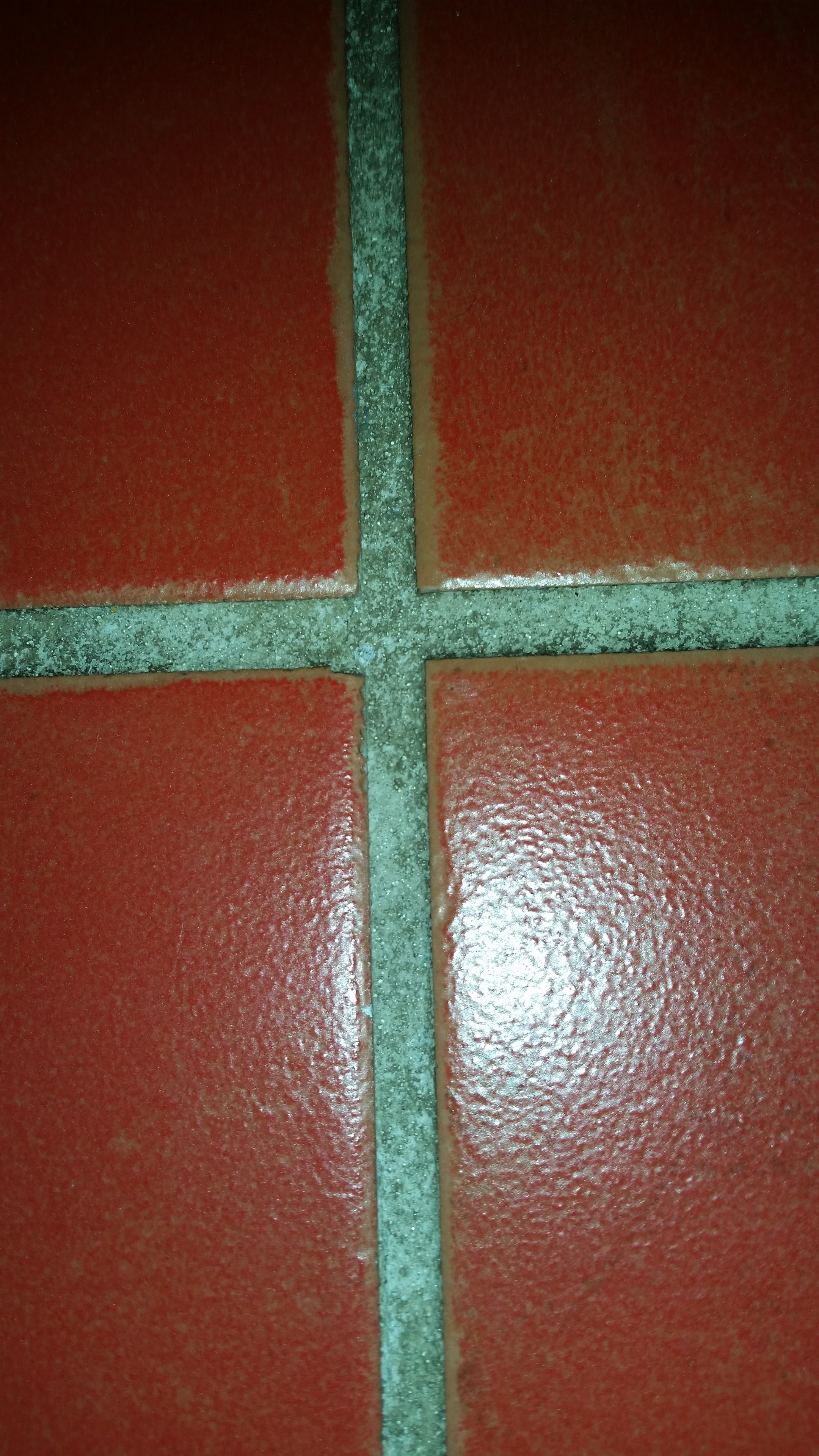 Red tiles with dirty discoloured grout before cleaning